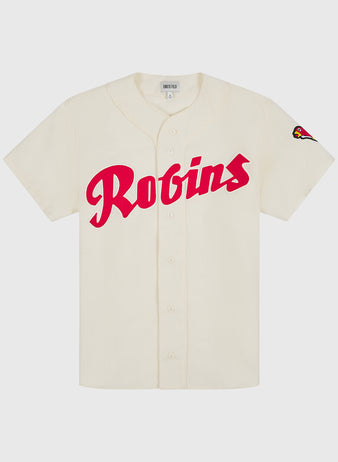 The Ebbets Field Shochiku Robins 1950 Authentic Wool Home Jersey features a cream-colored design with bold red Robins script across the front and a small cardinal bird patch on the left sleeve. Inspired by the iconic 1950 Japanese baseball jersey, this classic piece boasts a traditional button-up front and short sleeves.
