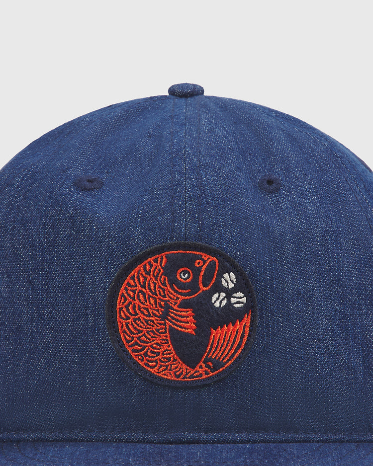 Introducing the Ebbets Field Hiroshima Carp Indigo Cotton Denim Twill Ballcap—a blue denim hat inspired by classic Japanese baseball style, featuring a circular patch with an embroidered red koi fish and three white coffee beans.