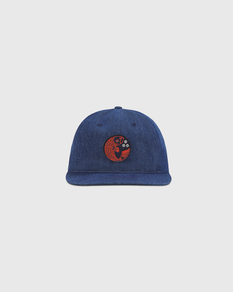 The Ebbets Field Hiroshima Carp Indigo Cotton Denim Twill Ballcap is shown against a plain light gray background, featuring a round red and black embroidered patch on the front with a stylized koi fish design—a subtle nod to Japanese baseball teams like the Hiroshima Carp.