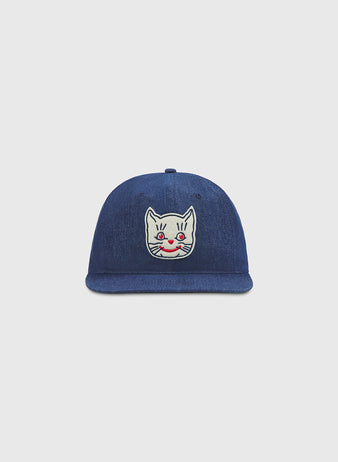 Ebbets Field Kansas City Katz Indigo Cotton Denim Ballcap with a white cartoon cat face patch—red cheeks and a small smile—centered on the front, paying tribute to the iconic Kansas City Katz of Katz Drugstore fame. Shown against a plain, light gray background.
