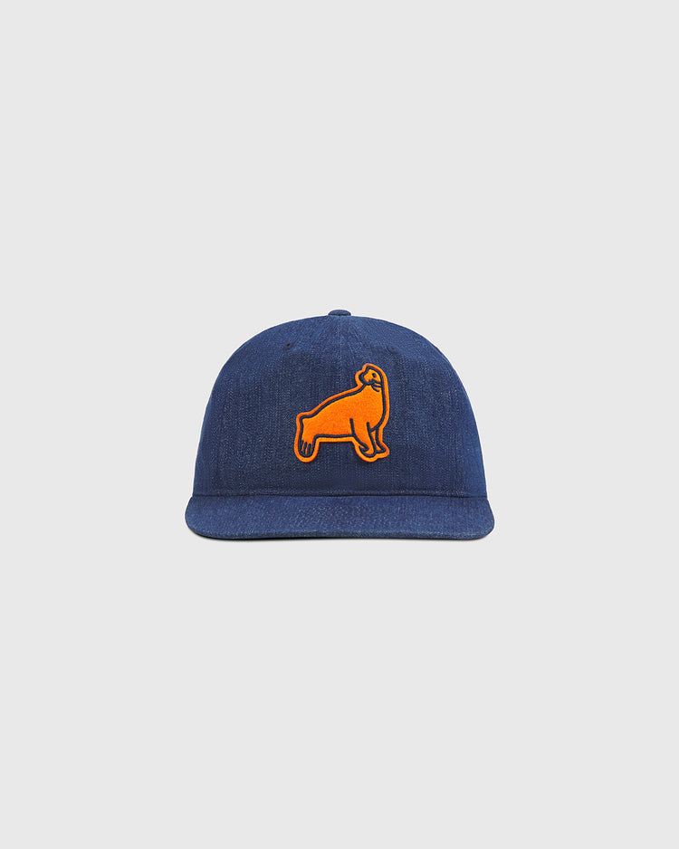 The Ebbets Field San Francisco Seals Indigo Cotton Denim Ballcap showcases a blue denim design with an orange patch of a standing dog on the front, evoking the classic style of historic Seals headwear and presented against a plain light gray background.