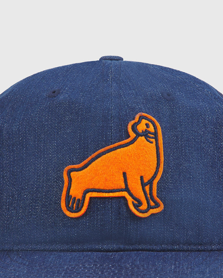 Close-up of the Ebbets Field San Francisco Seals Indigo Cotton Denim Ballcap, a blue denim hat with an orange embroidered seal patch on the front, inspired by the classic San Francisco Seals look.