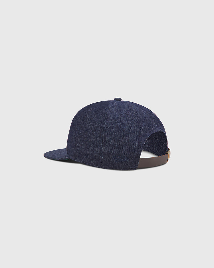 The Fuji Athletic Club Indigo Cotton Denim Ballcap by Ebbets Field features a dark blue denim design with a curved brim and an adjustable brown strap at the back, shown against a plain light gray background. Inspired by the heritage of Japanese Baseball, this classic cap makes a standout addition to any collection.