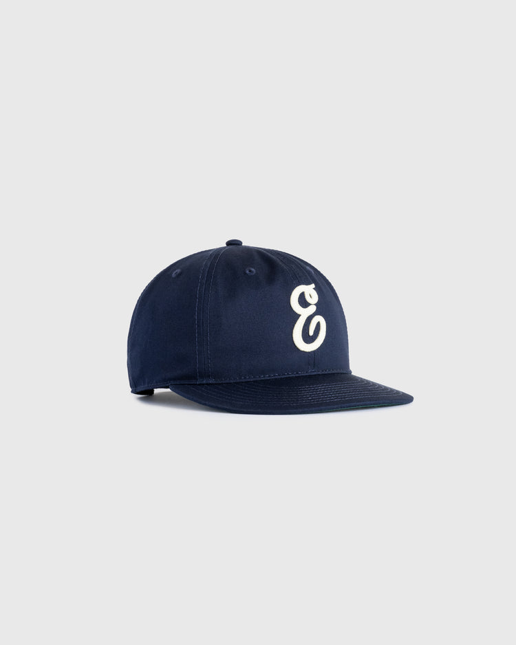 The Ebbets Field Flannels Ebbets Felt E Cotton Twill Ballcap features navy blue cotton twill with a white felt lowercase e on the front, ideal for daily wear and pictured on a plain light gray background.