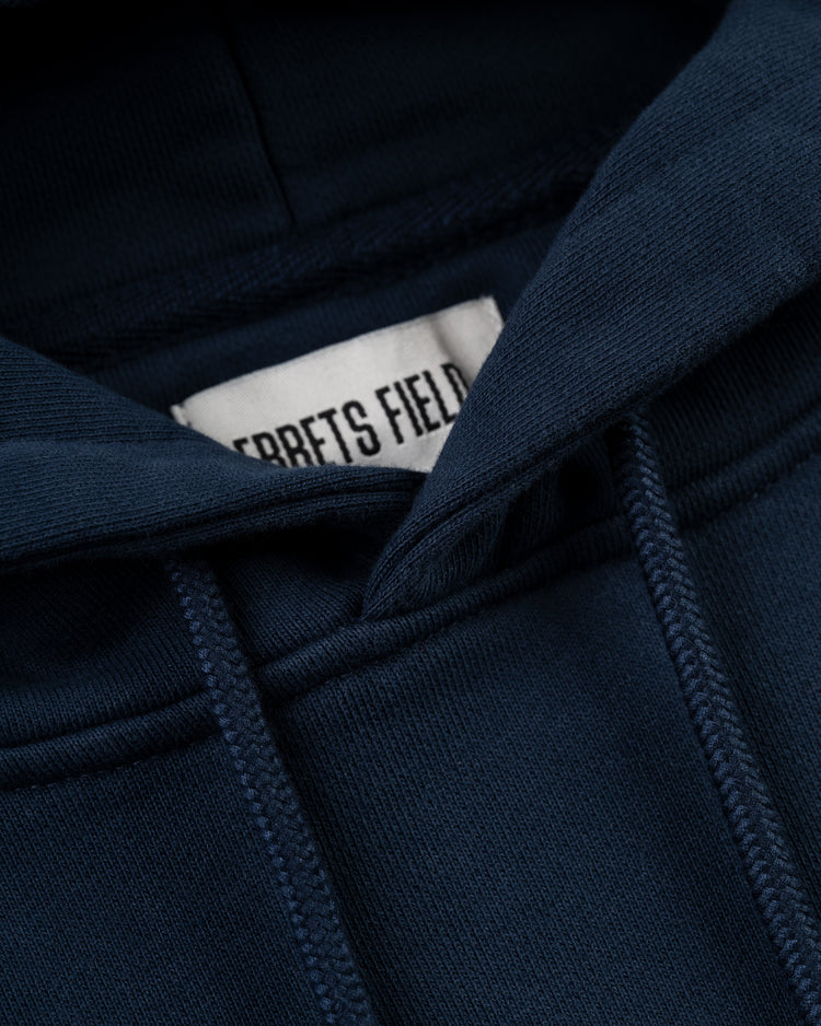 A close-up of the New York Black Yankees Embroidered NY Heavyweight Cotton Terry Pullover Hoodie by Ebbets Field in navy, showing the hood, drawstrings, and a partially visible label, inspired by classic Negro Leagues apparel.
