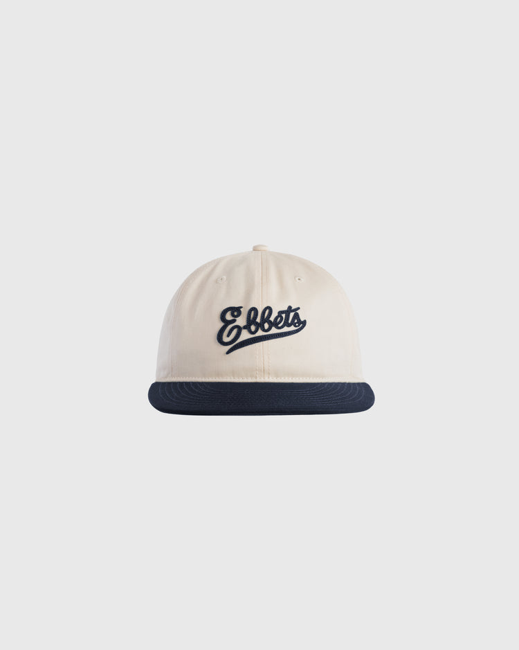 The Ebbets Felt Script Cotton Twill Ballcap by Ebbets Field Flannels is cream-colored with a dark blue brim and features Ebbets embroidered in dark blue script on the front.