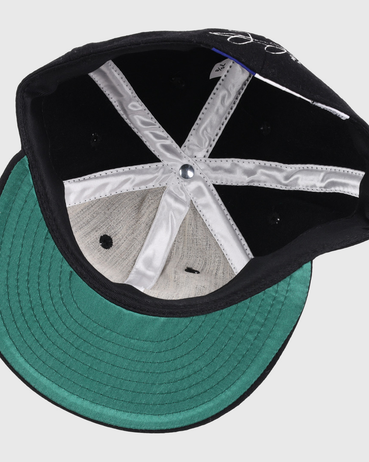 Inside view of the Ebbets Field Flannels Frank Thomas Signature Series Ballcap - Black features a green brim, white lining, black ventilation holes, and a silver crown button.