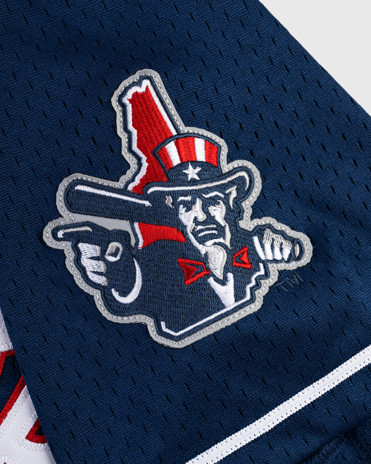 The Ebbets Field VLAD GUERRERO JR BUTTON UP MESH JERSEY in navy features a patch with a stern Uncle Sam, red, white, and blue hat, holding a bat over Idahos red silhouette on breathable mesh fabric.