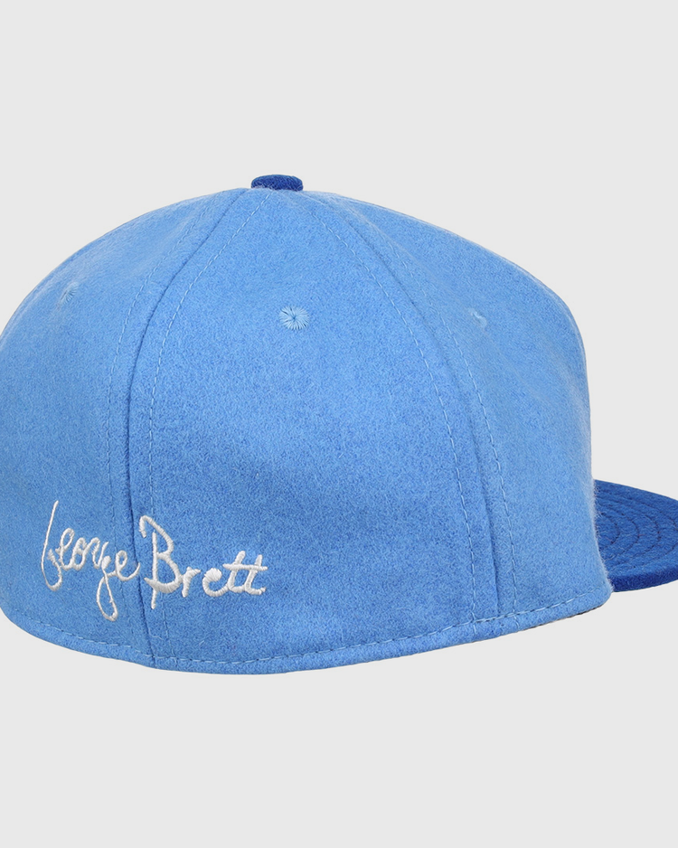 The Ebbets Field Flannels George Brett Signature Series Ballcap features a light blue vintage wool crown, darker blue brim, and white script embroidery of George Brett’s signature—a tribute to the Hall of Fame legend.