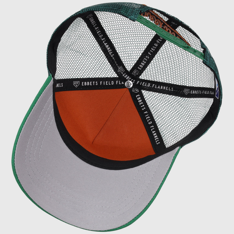 The inside view of the Greensboro Grasshoppers MiLB Trucker Ballcap by Ebbets Field shows green, gray, and orange mesh panels, an orange sweatband, and black straps labeled “EBBETS FIELD FLANNELS.”.