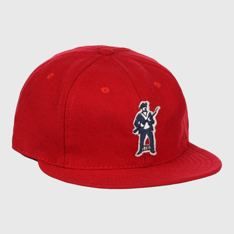 The EFF Greensboro Patriots 1922 Vintage Ballcap is a bright red hat with an embroidered figure in a suit holding a guitar on the front left side.