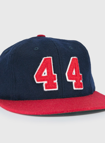 The Ebbets Field Flannels Hank Aaron 1957 Signature Series Ballcap is a vintage-style wool cap in navy with a red brim and bold red-and-white “44” on the front, inspired by baseball legends and proudly made in the USA.
