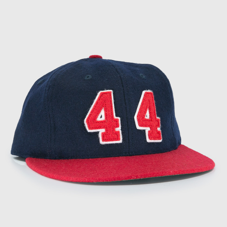 The Ebbets Field Flannels Hank Aaron 1957 Signature Series Ballcap is a vintage-style wool cap in navy with a red brim and bold red-and-white “44” on the front, inspired by baseball legends and proudly made in the USA.
