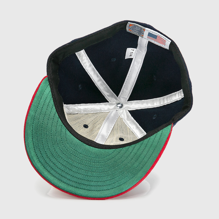 An inside view of the Ebbets Field Flannels Hank Aaron 1957 Signature Series Ballcap shows a green underbrim, red trim, white stitched panels, silver top button, and an American flag tag, highlighting its USA-made quality.