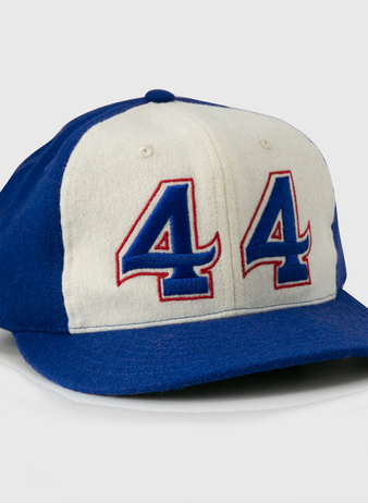 The Hank Aaron 1973 Signature Series Ballcap by Ebbets Field Flannels is a vintage-style wool cap, made in the USA, featuring blue/white panels and “44” in blue and red outlined on the front.