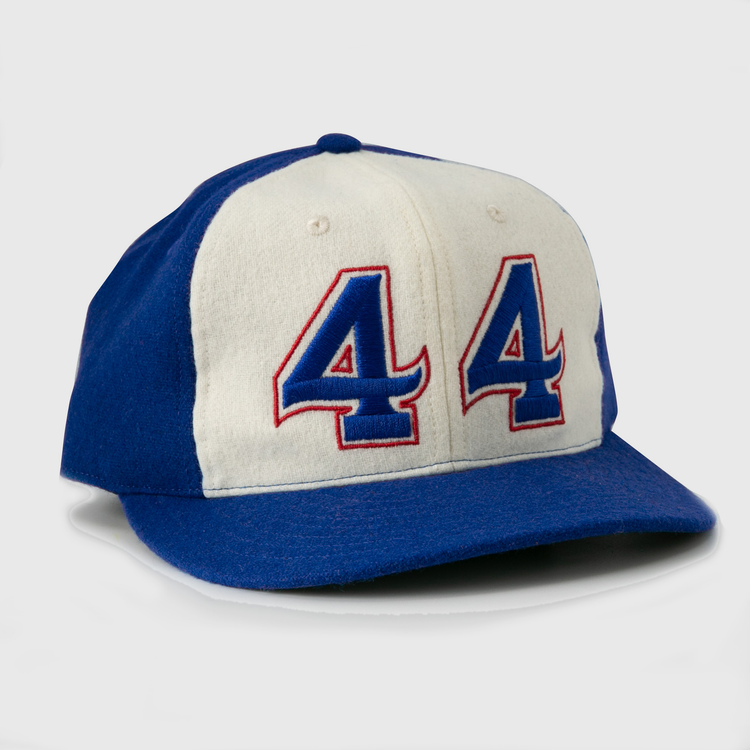 The Hank Aaron 1973 Signature Series Ballcap by Ebbets Field Flannels is a vintage-style wool cap, made in the USA, featuring blue/white panels and “44” in blue and red outlined on the front.