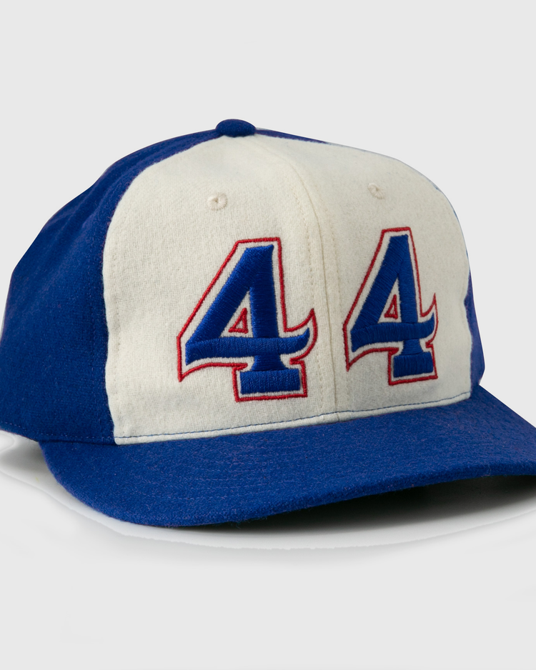 The Hank Aaron 1973 Signature Series Ballcap by Ebbets Field Flannels is a vintage-style wool cap, made in the USA, featuring blue/white panels and “44” in blue and red outlined on the front.