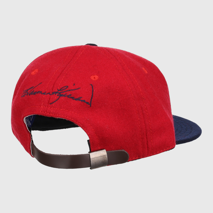 The Ebbets Field Flannels Harmon Killebrew Signature Series Ballcap, in red and navy vintage wool, is shown from the back with a brown adjustable strap, metal clasp, and black signature embroidery above the opening.