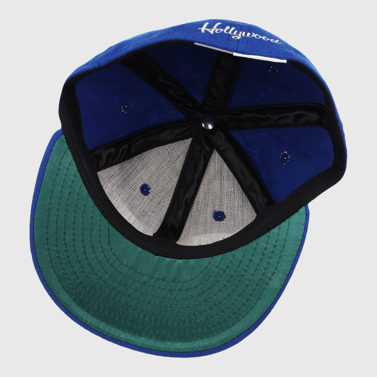 The image shows the inside of an EFF Hollywood Stars Letterhead Wool Vintage Ballcap, featuring a blue wool exterior, green underbrim, black banding, white stitching, and Hollywood partially visible on the inner front panel.