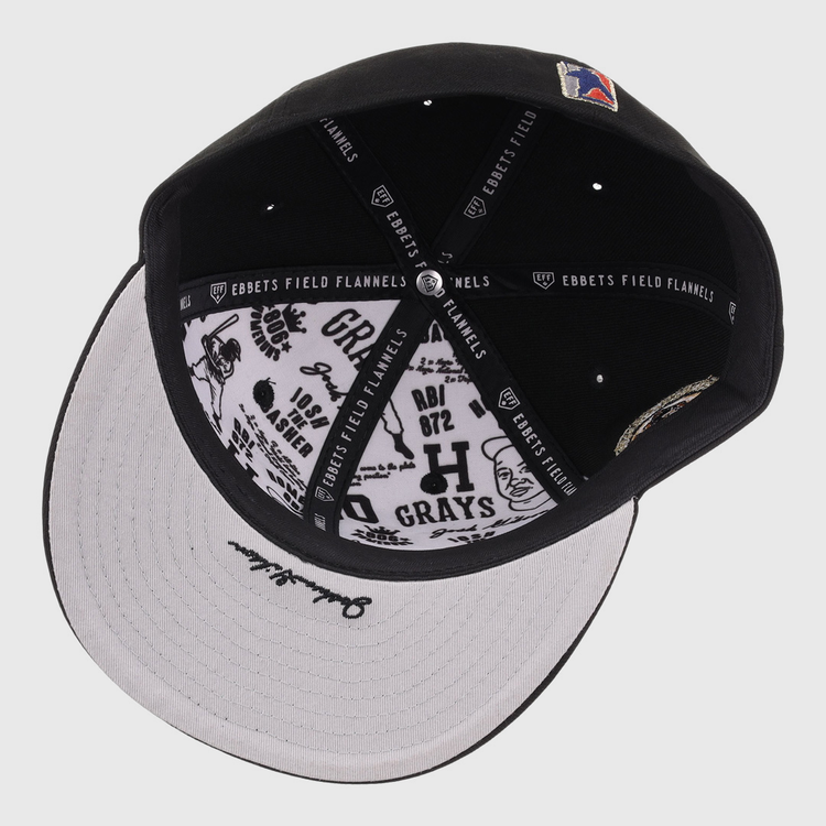 The Homestead Grays Josh Gibson Fitted Ballcap - Black by EFF is shown from above, highlighting its inner lining with EFF branding and black graphic designs and text on the white underside of the brim.