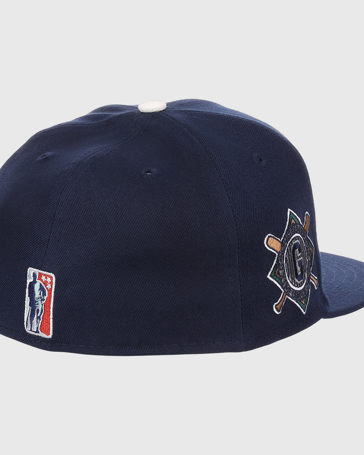 The EFF Homestead Grays NLB Flip Fitted Ballcap features dark blue fabric, a white top button, the classic MLB logo at the back, and a side patch with crossed bats and a “G” honoring Pittsburgh’s legendary Negro League team.