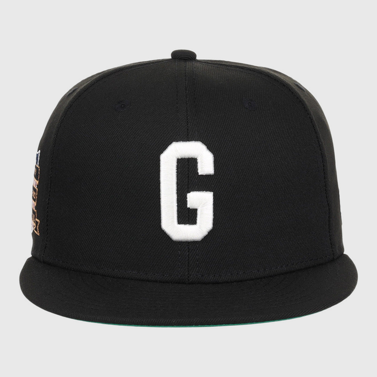 The Ebbets Field Homestead Grays NLB Tc Fitted Ballcap is a black cap with a flat brim, featuring a large white embroidered letter G on the front and minimal visible detailing.