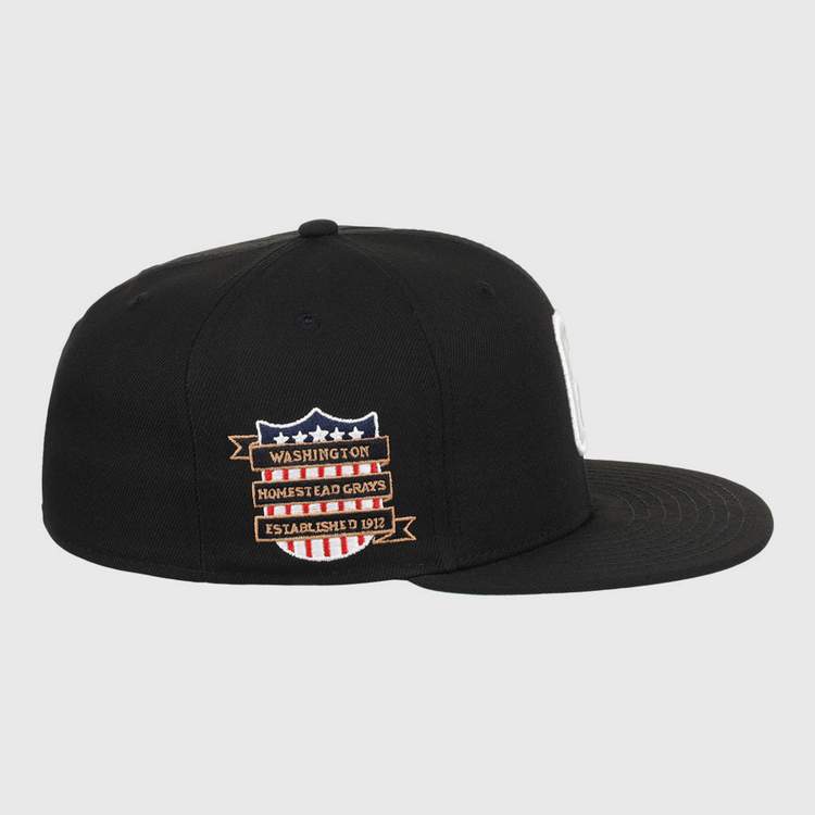 The Ebbets Field Homestead Grays NLB Tc Fitted Ballcap is a black, flat-brim cap with side embroidered patches—a shield with stars and stripes, plus banners reading Washington, Homestead Grays, and Established 1912.