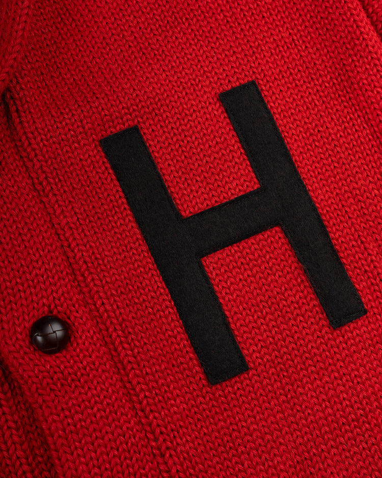 A close-up of the EFF Harvard University 1940 Wool Shawl Collar Sweater shows red knit fabric, a large black letter H, and a black button on the left side.