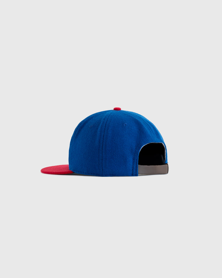 The EFF Hollywood Stars 1949 Authentic Wool Ballcap, blue with a red brim and black adjustable strap, is shown from the back against a plain light grey background.