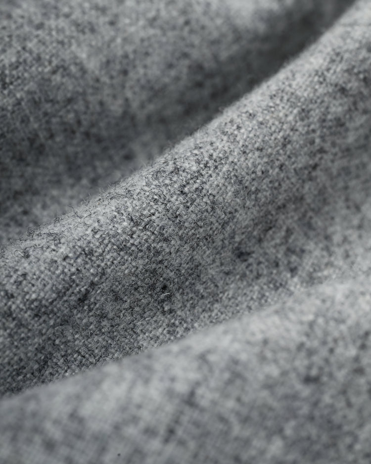A close-up of gray textured fabric shows soft folds, highlighting the woven fibers and speckled look of the Ebbets Field Flannels Homestead Grays 1944 Authentic Wool Road Baseball Jersey.