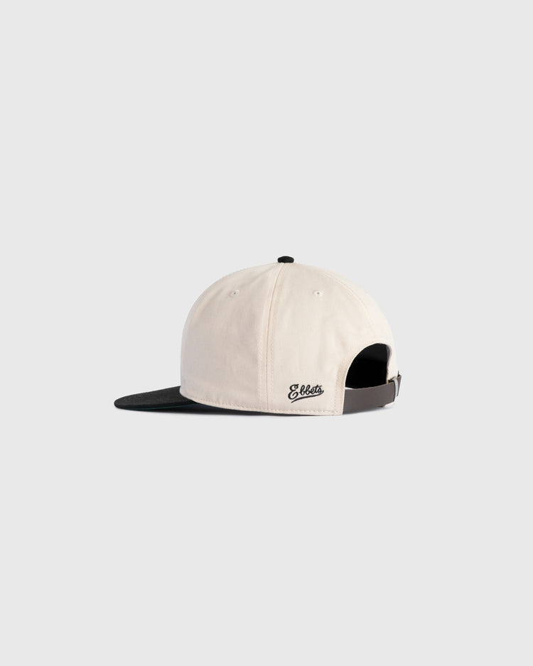The Ebbets Field Flannels Homestead Grays Embroidered Two Tone Cotton Twill Ballcap is cream-colored with a black brim, shown from the back with an adjustable strap and Ebbets embroidered in black near the opening.
