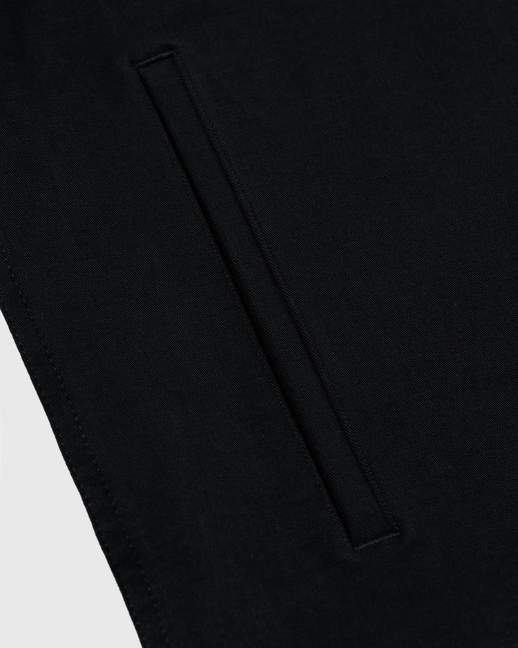 Close-up of the Ebbets Field Flannels Homestead Grays Cotton Grounds Crew Jacket in black twill, showcasing a single welt pocket with precise stitching and a smooth, minimalist design inspired by classic Homestead Grays style.