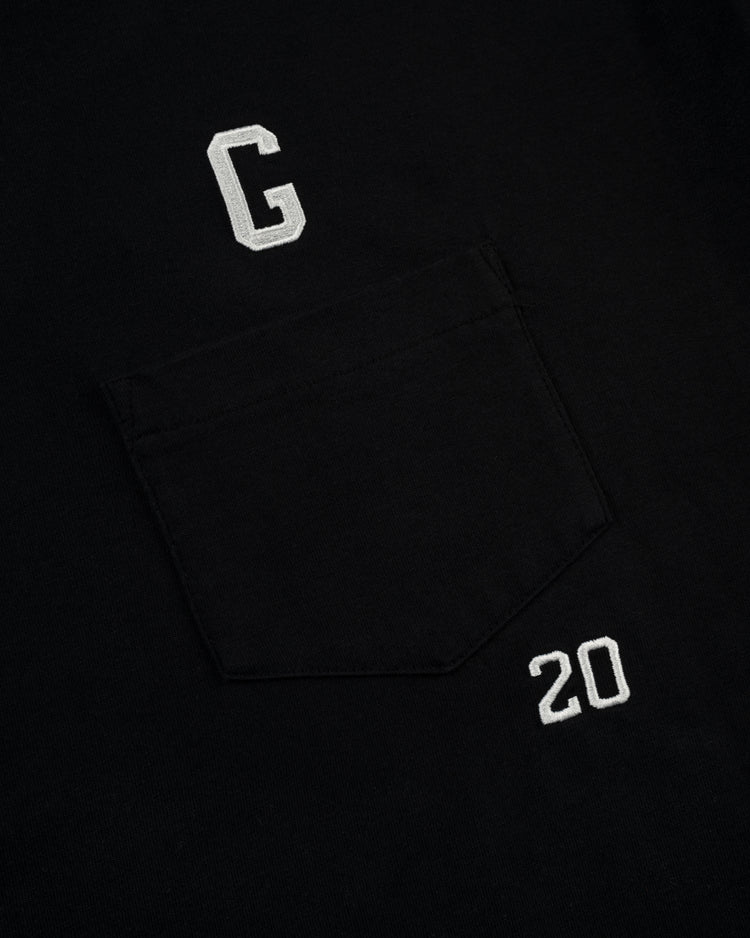 The Ebbets Field Flannels Homestead Grays Embroidered G Long Sleeve Pocket Tee is a black shirt with a chest pocket, featuring a white embroidered G above and 20 below—a tribute to Josh Gibson and classic Negro Leagues style.
