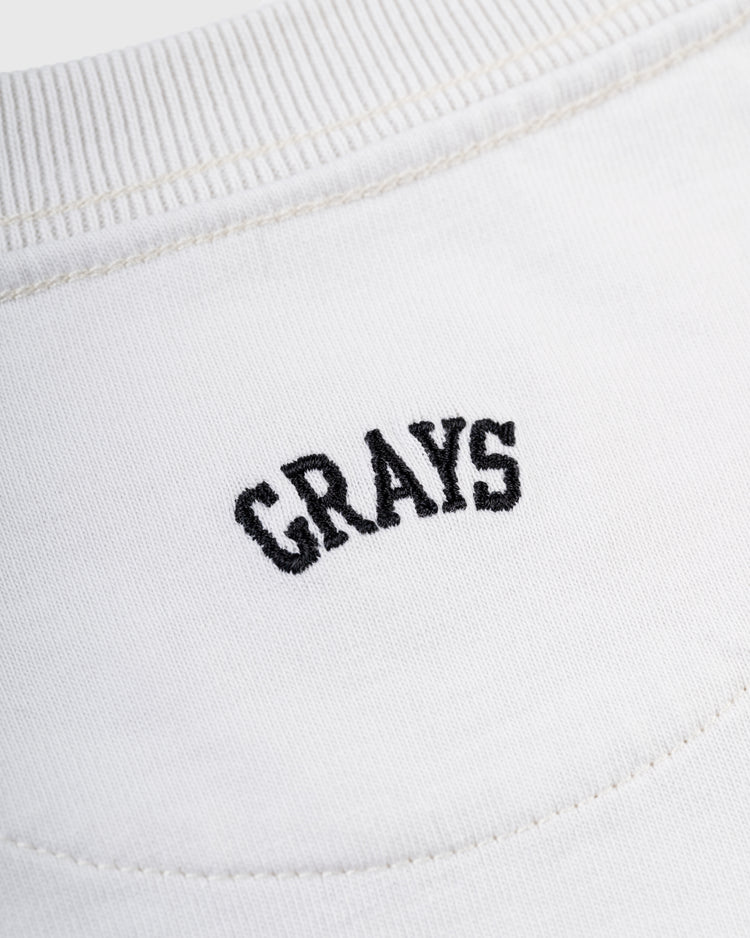 Close-up of the Ebbets Field Flannels Homestead Grays Embroidered G Long Sleeve Pocket Tee, featuring GRAYS in black letters above a seam—honoring Josh Gibson and the legacy of the Negro Leagues Baseball Museum.