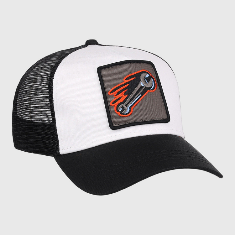 The Inland Empire 66Ers MiLB Trucker Ballcap by Ebbets Field is a black and white hat with a mesh back and a front patch showing a flaming wrench on a gray background.