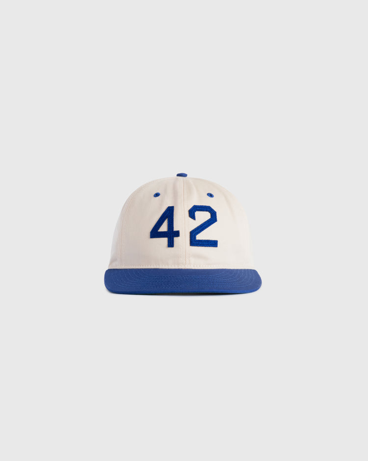 The Ebbets Field Jackie Robinson Day ‘42’ Cotton Twill Ballcap features a white crown, blue brim, and bold blue 42 on the front, honoring baseballs legacy—displayed against a plain light background.