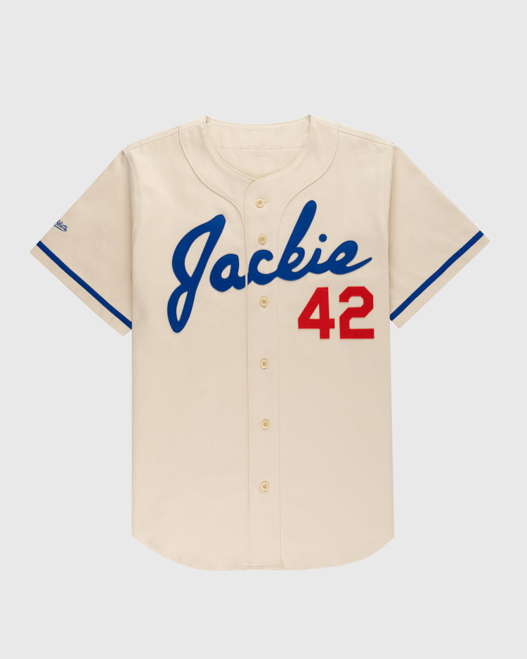 The Ebbets Field Jackie Robinson Cotton Twill Baseball Jersey features a cream color, blue trim, “Jackie” in blue script on the front, and red 42 on the right—an iconic tribute to baseball legend Jackie Robinson.
