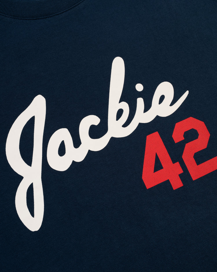 The Ebbets Field Jackie Robinson Script 42 Short Sleeve Tee features “Jackie” in large white script and a bold red 42 on navy, honoring Robinson’s legendary MLB and Brooklyn Dodgers legacy.