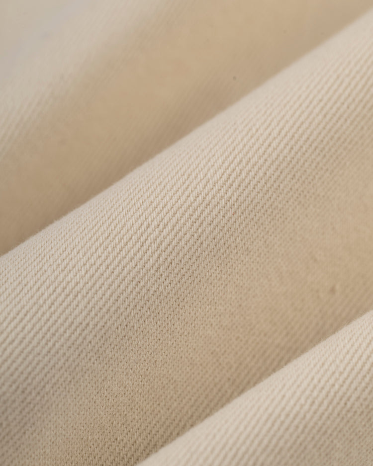 Close-up of the Ebbets Field Jackie Robinson Cotton Twill Baseball Jersey, featuring beige fabric with a fine diagonal weave pattern, evoking vintage baseball style and a soft, textured feel with gentle folds.