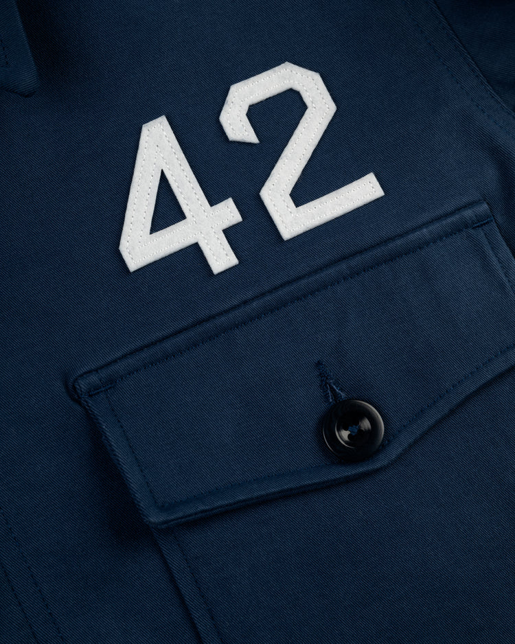 Close-up of the Ebbets Field Jackie Robinson Cotton Grounds Crew Jacket—navy blue with a large white number 42 above a buttoned front pocket, inspired by the iconic Jackie Robinson jacket.
