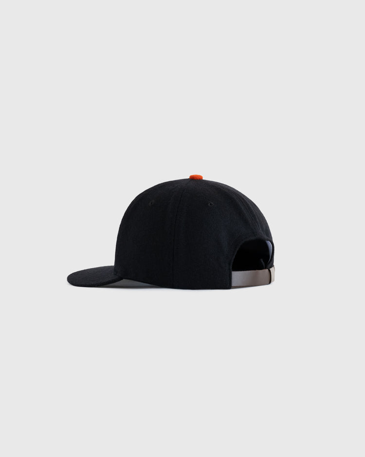 The EFF Jersey City Giants 1950 Authentic Wool Ballcap, shown from the back at an angle, is black with an orange top button, features an adjustable strap, and is set against a plain light gray background.