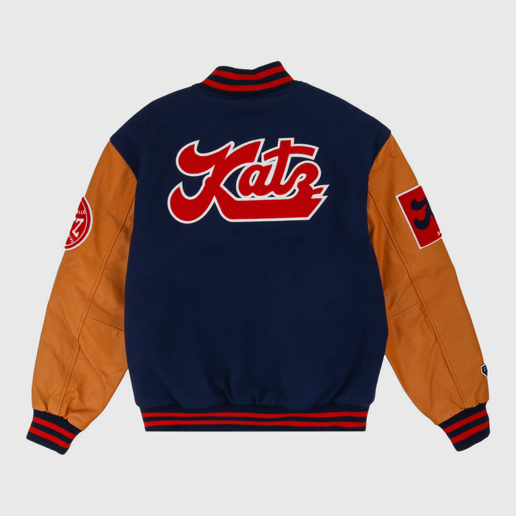 The Ebbets Field Kansas City Katz Dna Varsity Jacket has a navy body, tan sleeves, red accents, a large red and white Katz patch on the back, and round plus square patches on the sleeves.