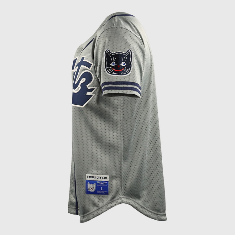 The Kansas City Katz EFF DNA Replica Button-Up Mesh Jersey by EFF features gray mesh fabric, navy and white sleeve trim, a black cat shoulder patch, and a Kansas City Katz label near the hem—honoring the iconic Katz Drugstore legacy.