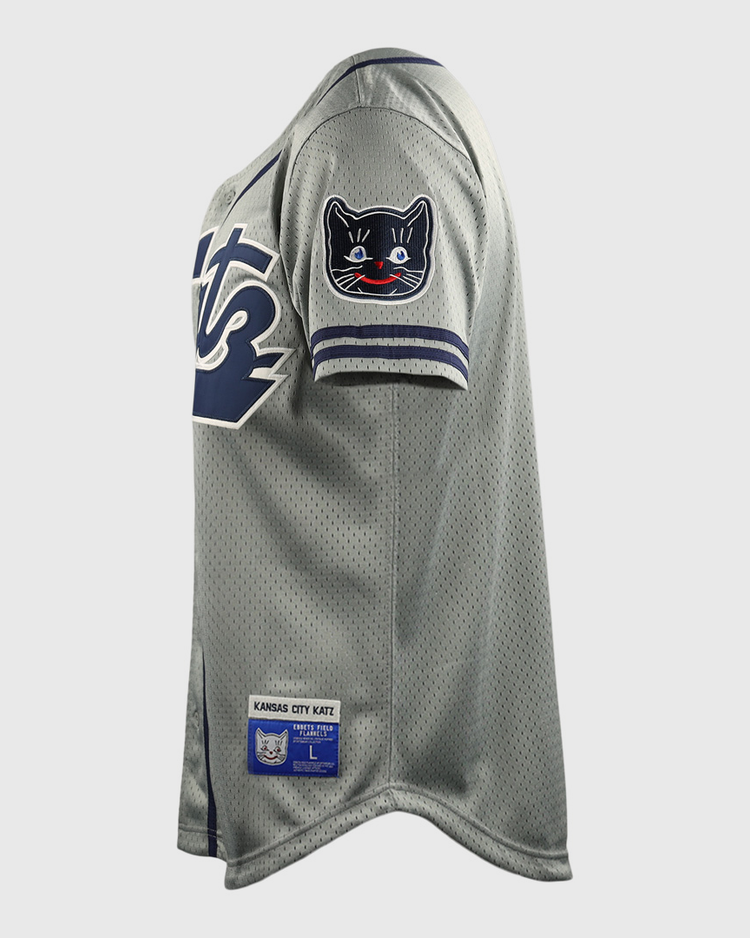 The Kansas City Katz EFF DNA Replica Button-Up Mesh Jersey by EFF features gray mesh fabric, navy and white sleeve trim, a black cat shoulder patch, and a Kansas City Katz label near the hem—honoring the iconic Katz Drugstore legacy.
