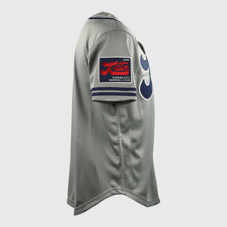 Side view of the Kansas City Katz EFF DNA Replica Button-Up Mesh Jersey by EFF, featuring a gray design, red and black patch on the sleeve, bold blue numbers on the front, and honoring the Ban Johnson Baseball League.