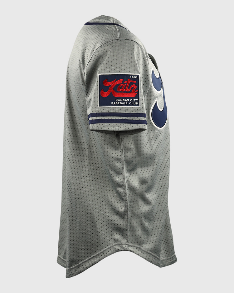 Side view of the Kansas City Katz EFF DNA Replica Button-Up Mesh Jersey by EFF, featuring a gray design, red and black patch on the sleeve, bold blue numbers on the front, and honoring the Ban Johnson Baseball League.