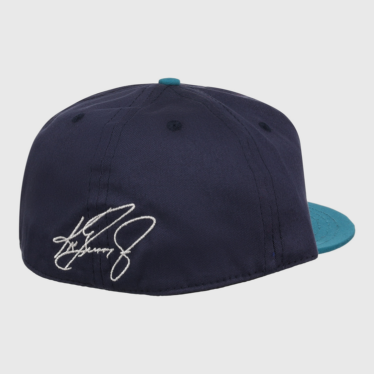 The Ebbets Field Flannels Ken Griffey Jr. 1995 Signature Series Ballcap is a navy wool cap with a teal brim, seen from the back, and features a white embroidered signature on the left side.