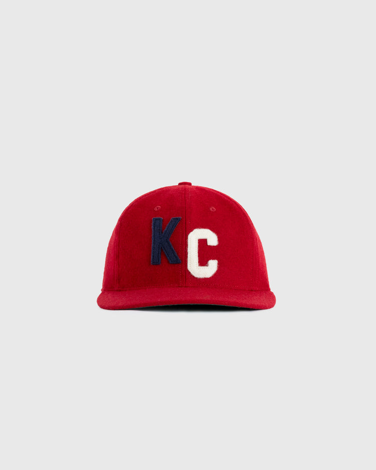 The EFF Kansas City Monarchs 1936 Authentic Wool Ballcap features a red design with bold blue K and white C embroidery, inspired by the original 1936 team cap, shown against a plain gray background.