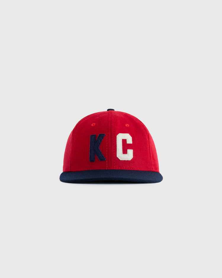 The Kansas City Monarchs 1954 Authentic Wool Ballcap by EFF features a red crown, navy blue brim, and large KC letters—K in navy, C in white—evoking classic Negro Leagues style against a plain light gray background.
