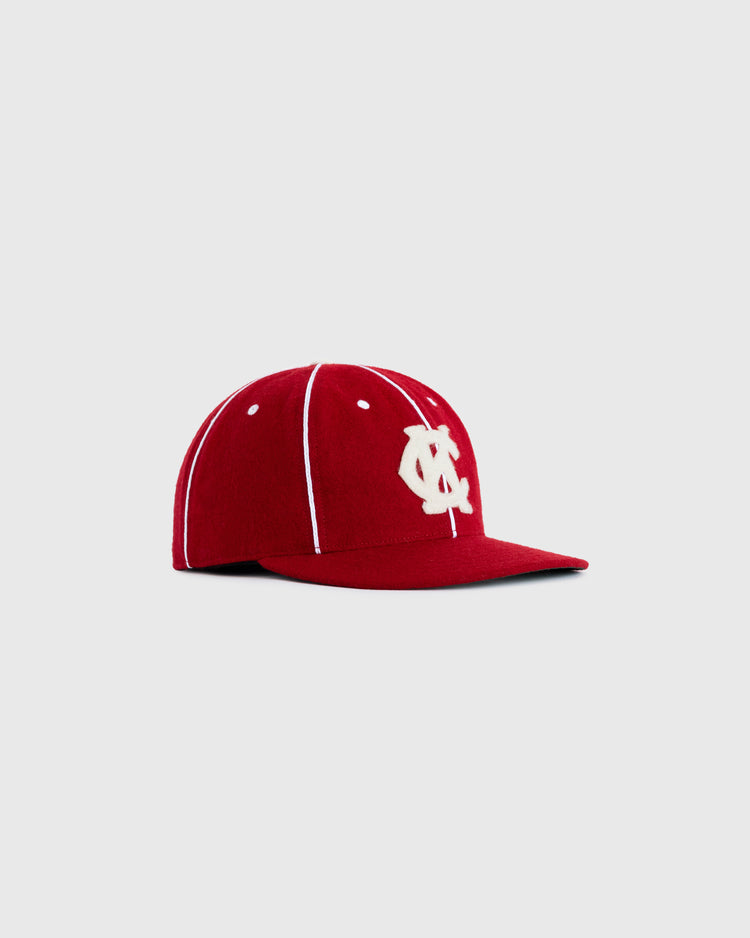 A Kansas City Monarchs 1949 Authentic Wool Ballcap by EFF, featuring red wool with white vertical stitching and a white interlocking OC logo on the front, shown on a plain light grey background.